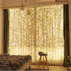 A sheer white curtain decorated with warm fairy lights indoors.
