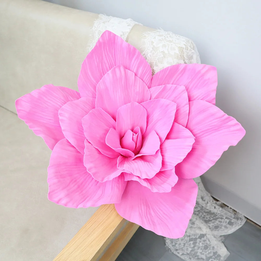 A large, vibrant pink foam rose flower is displayed on a light-colored surface.