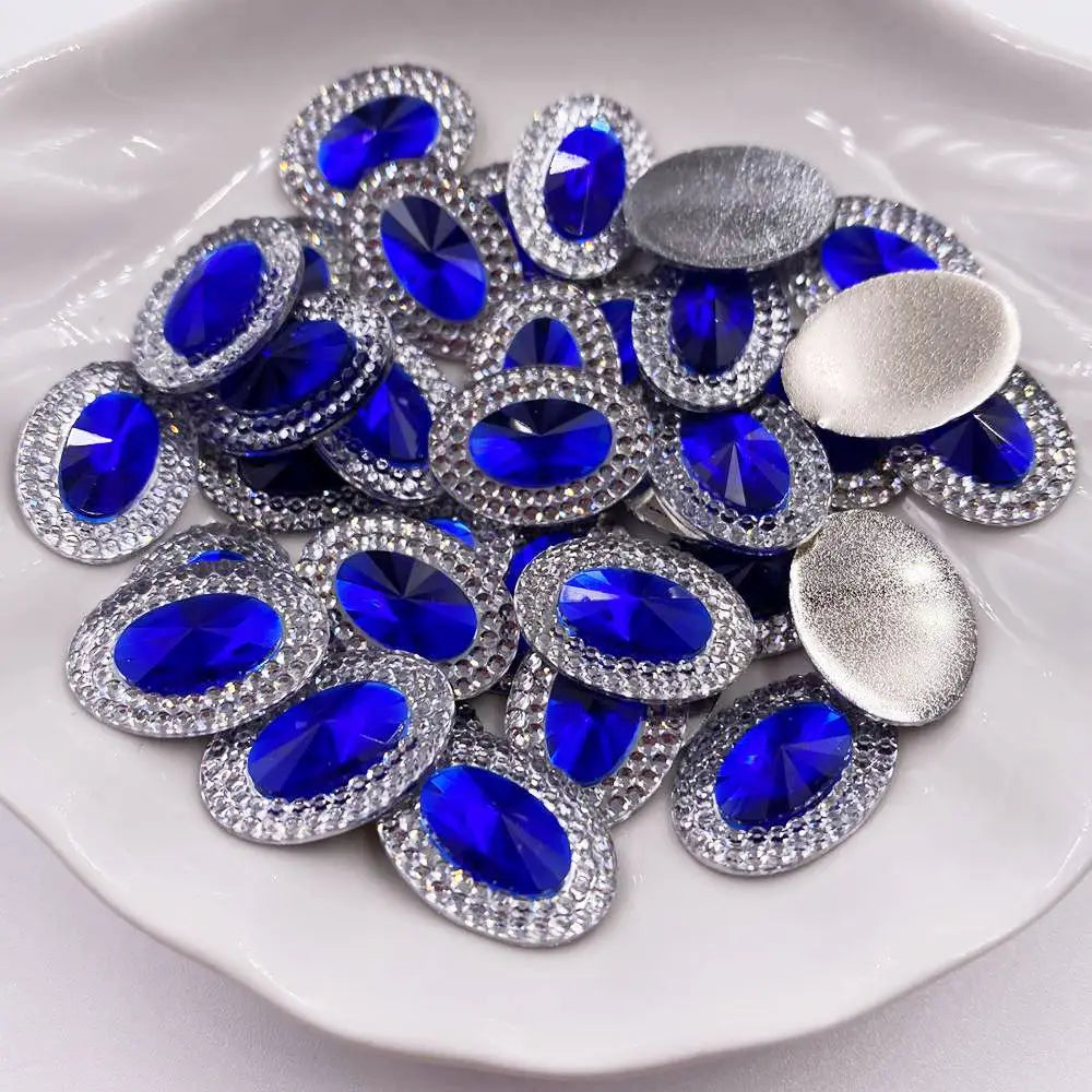 A pile of round and oval blue gemstones set in silver rhinestone flatbacks on a white plate.