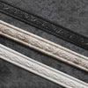 Three strips of white and black decorative corner wall trim strips laid diagonally on a dark gray textured surface.
