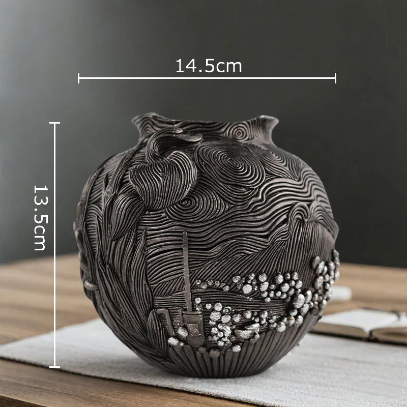 A dark gray resin vase with intricate swirling lines and textured surface, displayed on a wooden table.
