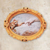 Vintage oval painting of a cat paw touching a human hand set in an ornate gold frame