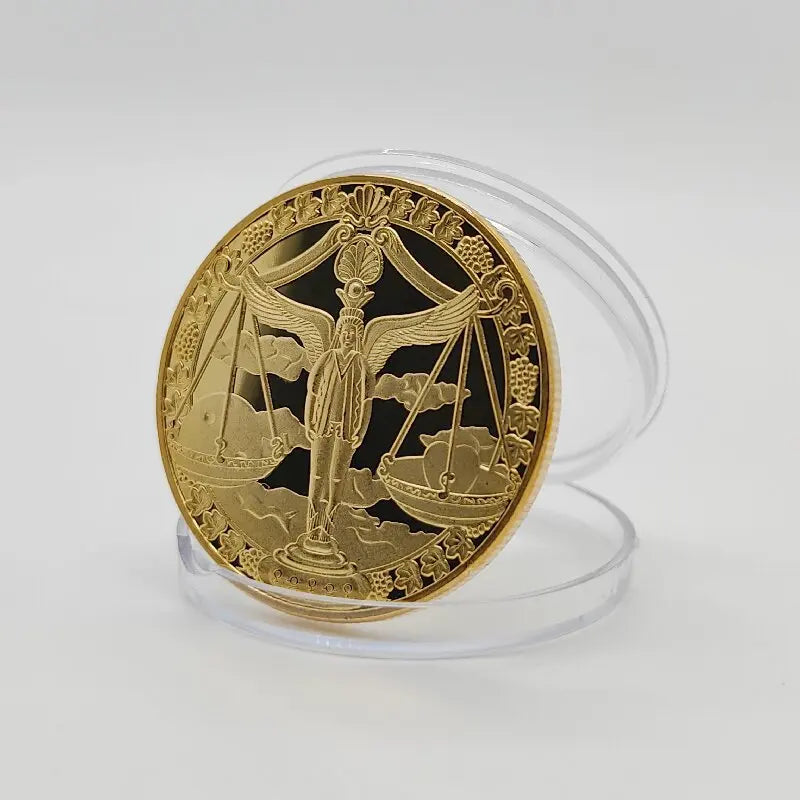 A round gold commemorative iron coin featuring a winged figure holding scales and a ship, displayed in a clear plastic holder