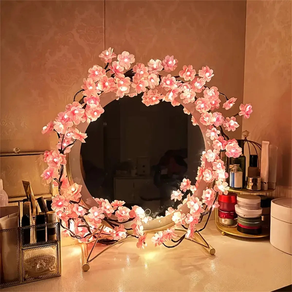 A circular wreath made of pink LED rattan string lights decorated with small flowers, displayed on a table.