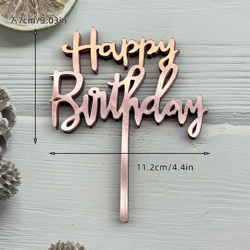A set of pink and gold acrylic birthday cake toppers spelling out Happy Birthday