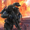 A Master Chief figure in armor stands ready with a rifle against a fiery, dramatic background.