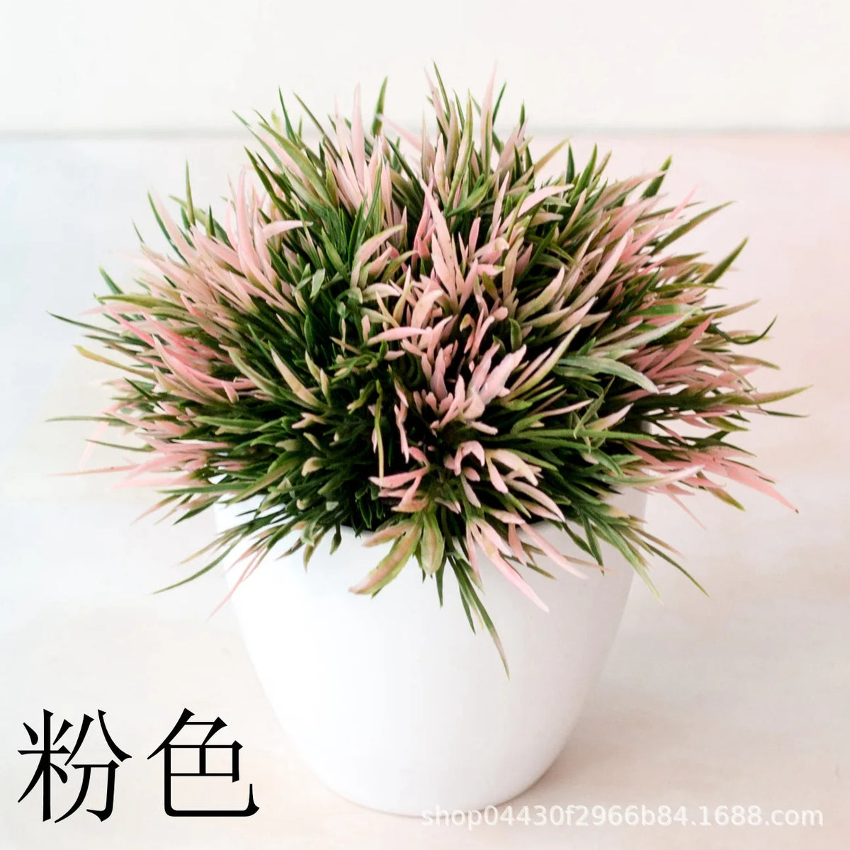 Un petit bonsaï artificiel dense avec du feuillage rose et vert dans un pot blanc.