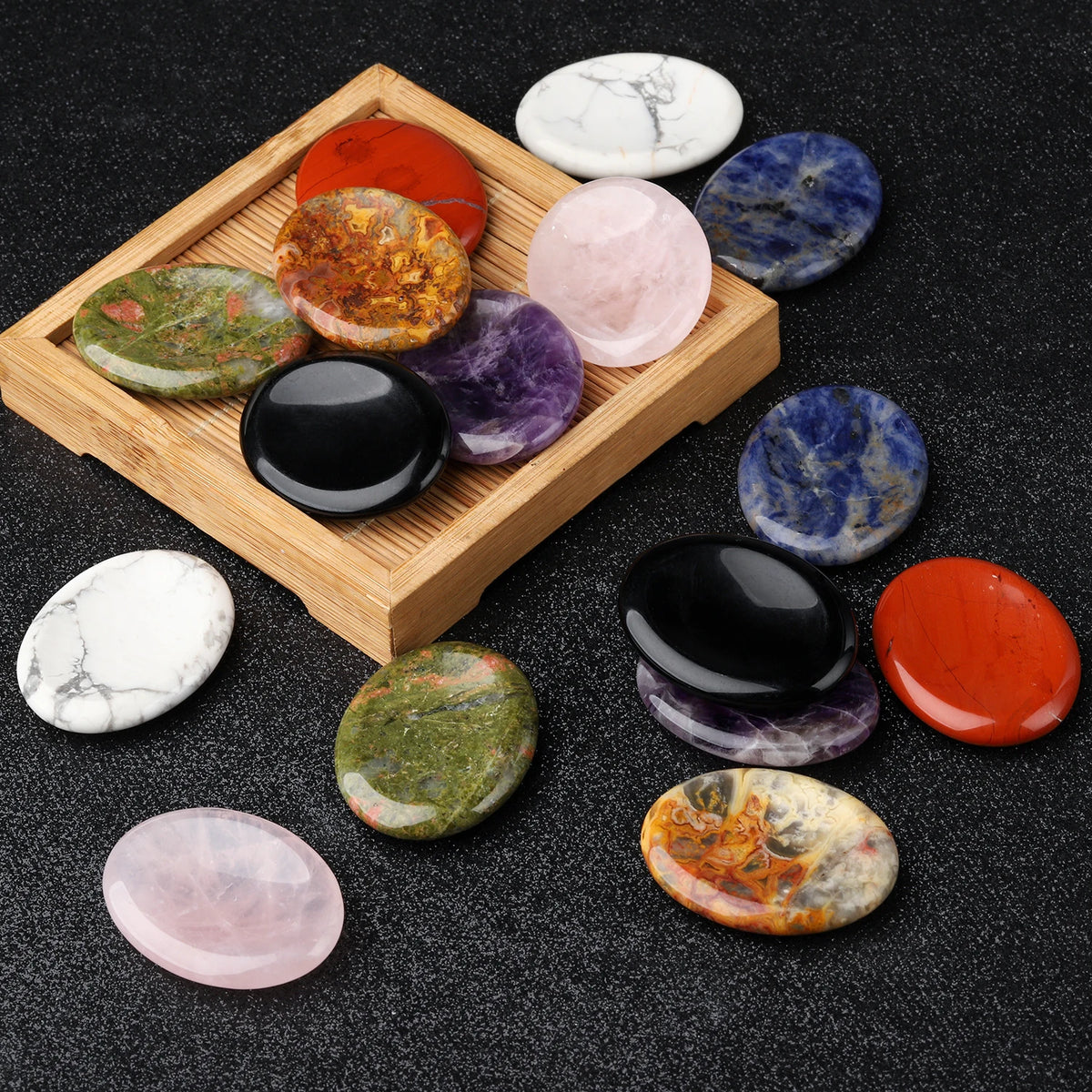 A collection of oval natural stone beads in various colors including orange, purple, green, and pink arranged in a wooden tra