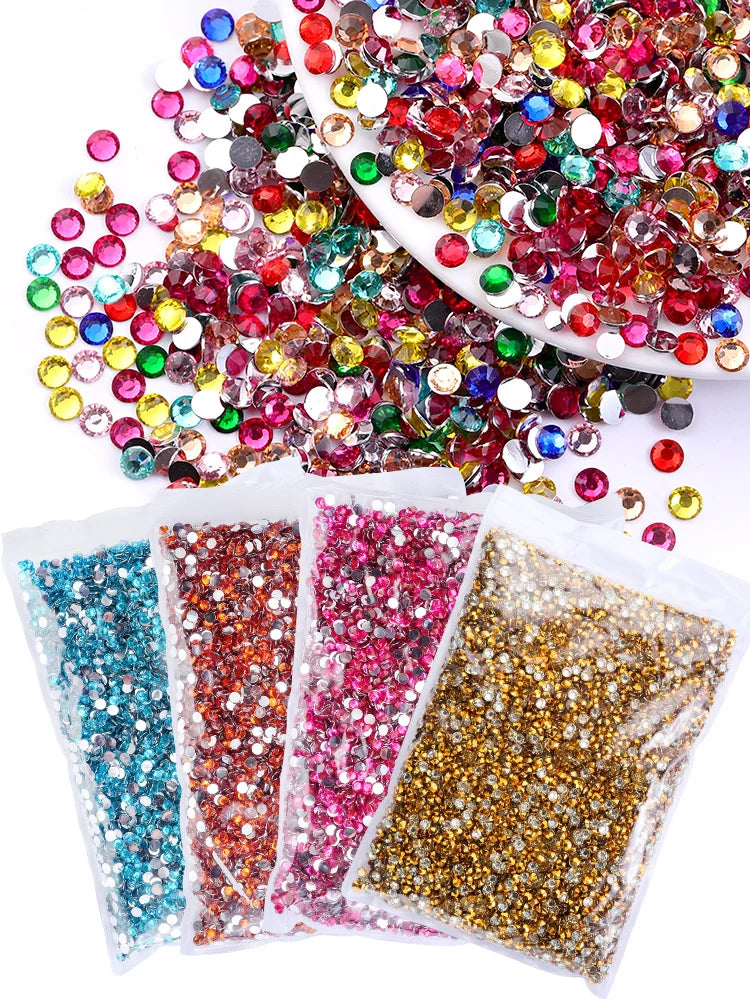 A collection of round flatback resin rhinestones in various colors like red, green, yellow, and pink scattered on a white sur