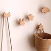 Decorative wooden animal hooks in various shapes like a cat and a star mounted on a white wall.