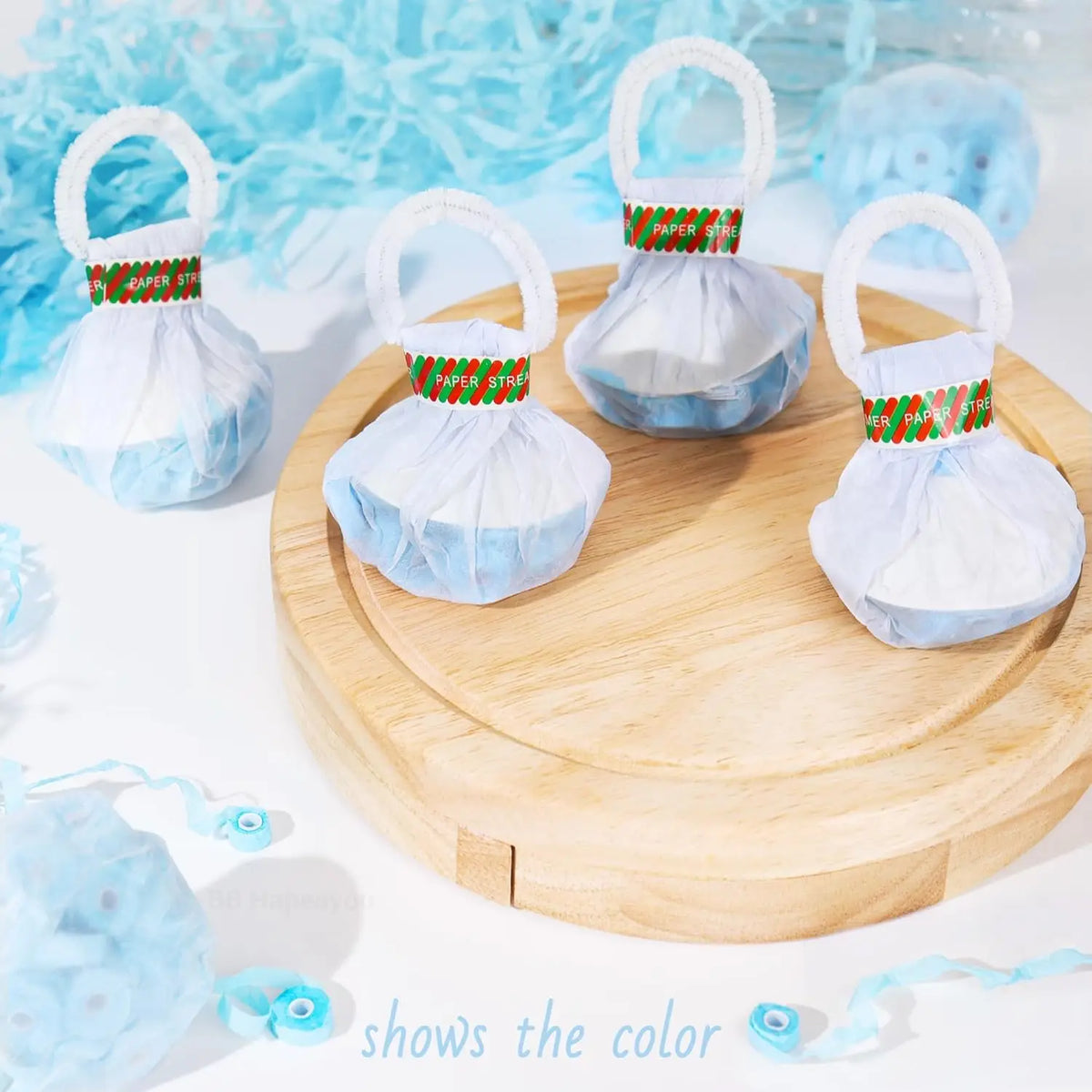 A wooden board displays ten white and light blue confetti streamer poppers with green accents.