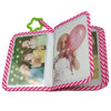 A pink and white striped photo album with a green elastic closure displaying baby photos.