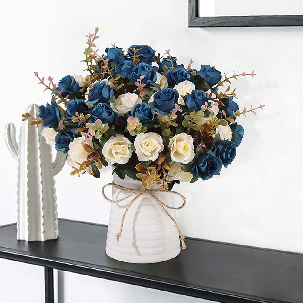 A bouquet of artificial silk roses in shades of blue, cream, and muted green arranged in a white vase.