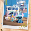 A photo of a Stitch character figurine in front of packaging and music sheet art.