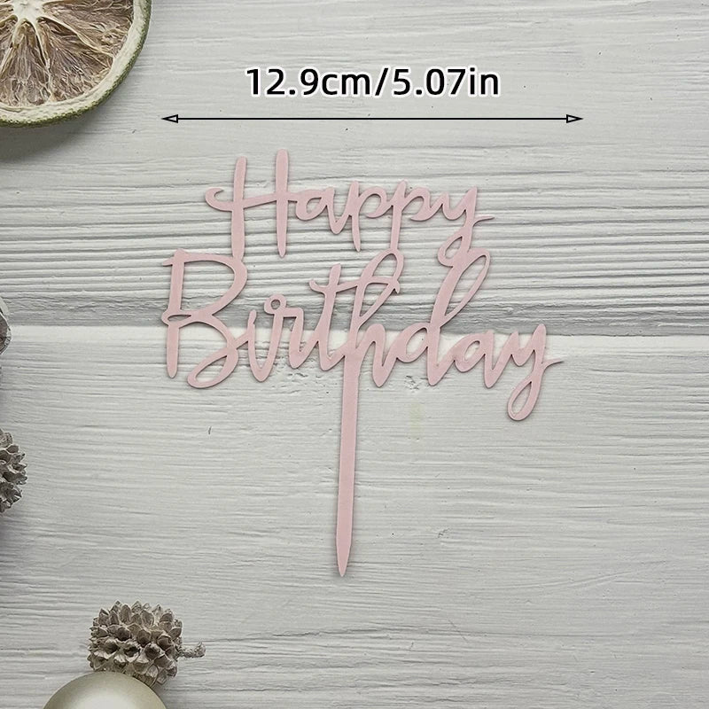 Pink acrylic birthday sign spelling out Happy Birthday on a light wooden background