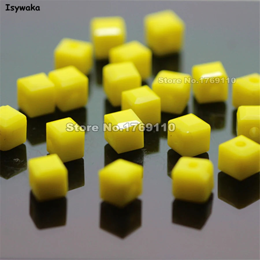 A collection of square cut yellow glass crystal beads for jewelry making arranged on a dark surface.