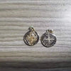 A pair of silver-toned religious pendants featuring St. Benedict imagery and dates.