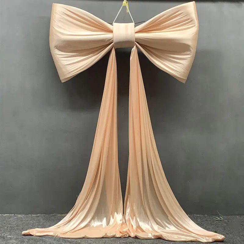 A large satin bow with long tulle drapes used for event decoration.