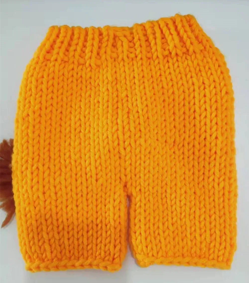 A bright orange hand-crocheted lion outfit set for a baby, featuring a textured knit design.