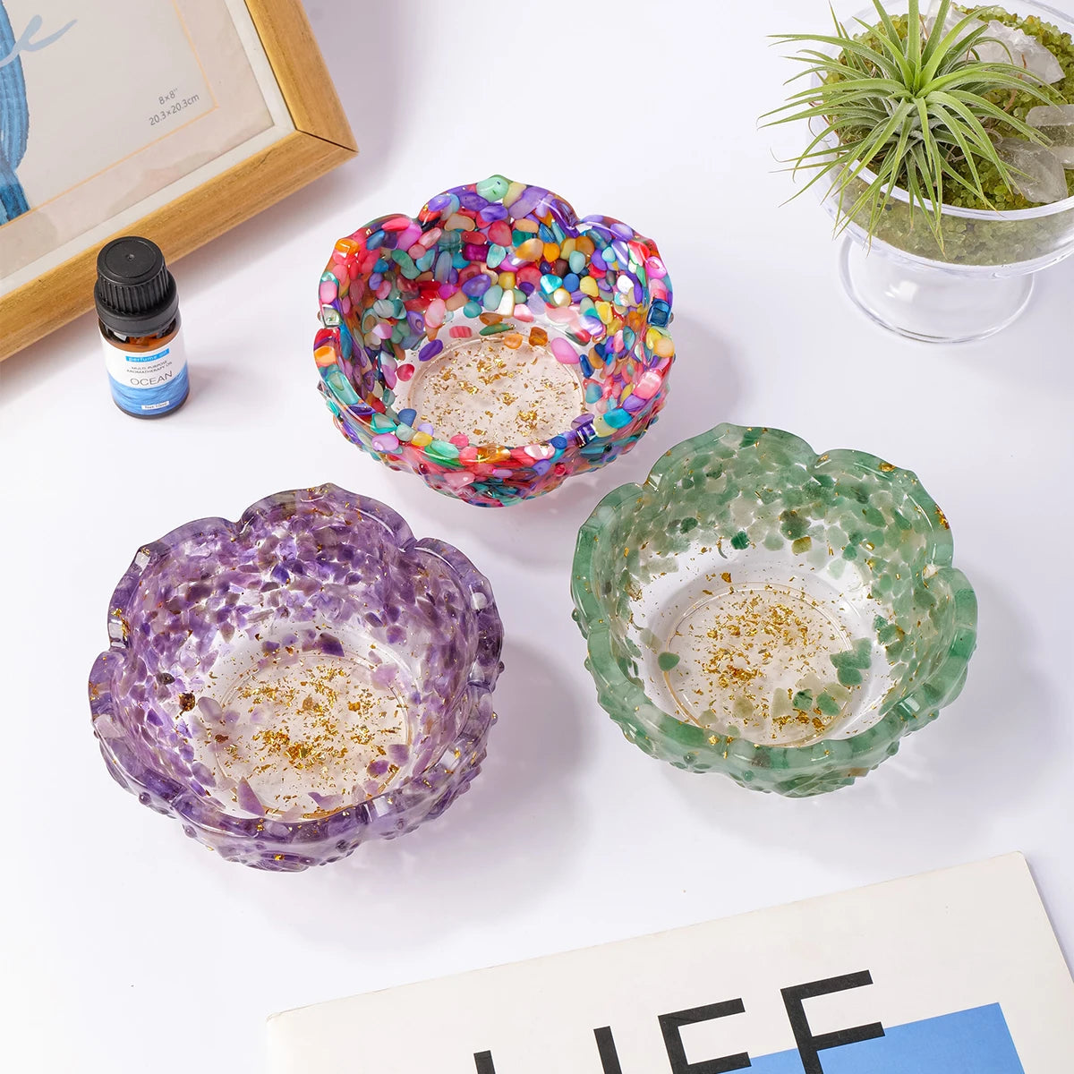 A collection of colorful crystal lotus bowls, including a multi-colored bowl and two green/purple bowls, displayed on a white