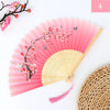 Pink and white floral design silk bamboo folding hand fan with a woven straw mat in the background