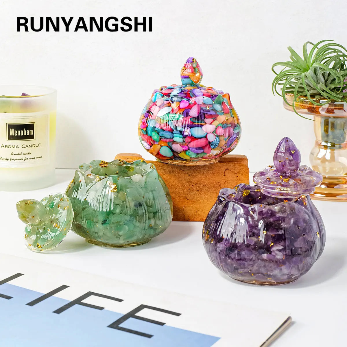 A collection of colorful crystal bowls and an aroma candle displayed on a white surface.
