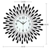 A modern minimalist metal wall clock with a black and silver sunburst design and Roman numerals.