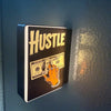 A black sign with the word HUSTLE in distressed white text and a graphic of a hand holding cash, mounted on a wall.