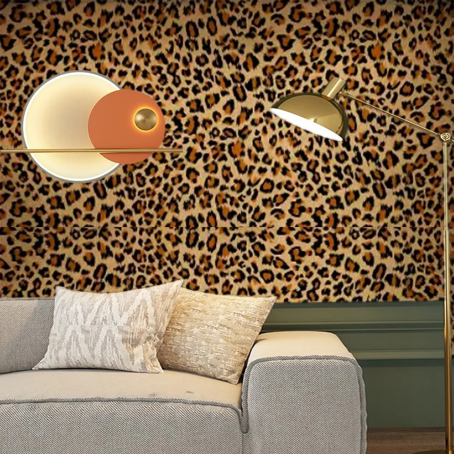 A modern living room featuring a leopard print wallpaper, a gold floor lamp, and a light-colored sofa.