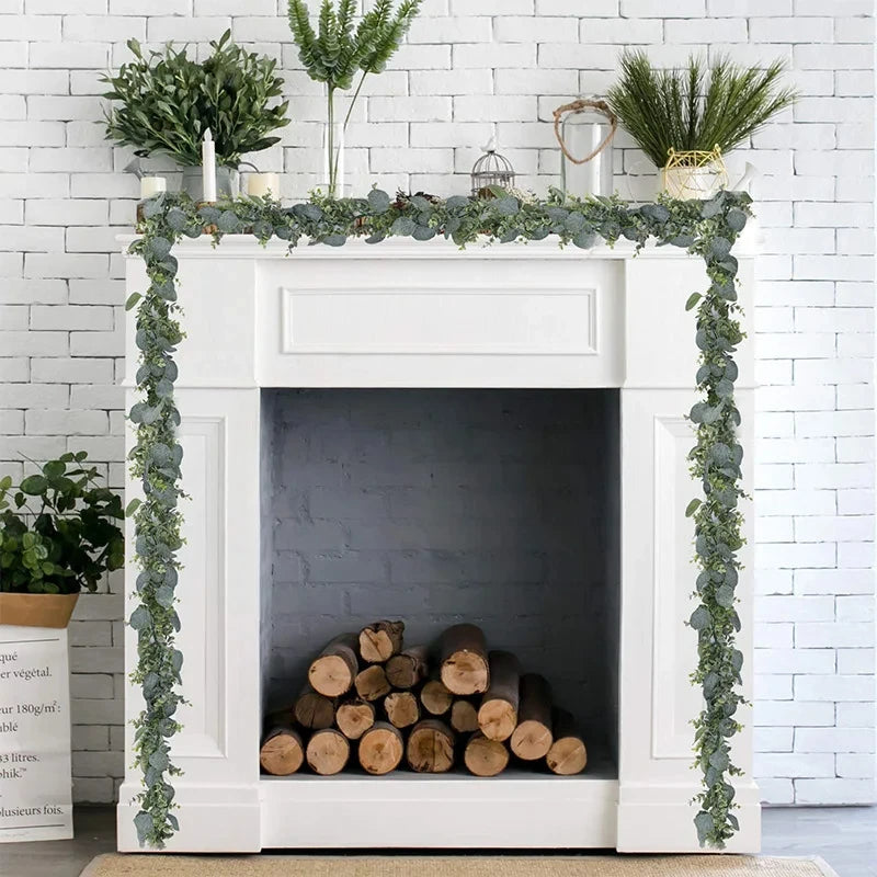 Artificial eucalyptus leaf garland draped over a white fireplace mantel decorated with greenery.