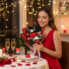 A woman holds a bouquet of handmade crochet rose flowers on a table decorated with red petals and candles.