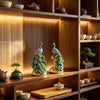 Elegant peacock statue with crystal tail feathers displayed on wooden shelves.