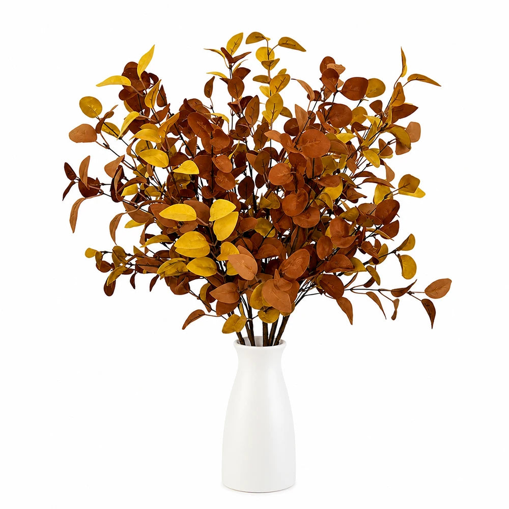 A bouquet of artificial fall eucalyptus stems in shades of brown and gold displayed in a white vase.
