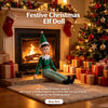 A festive Christmas elf doll decoration with lights sitting in front of a fireplace surrounded by wrapped gifts and a decorat
