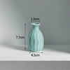A light blue ceramic mini vase with a rounded body and narrow neck, shown against a white background.