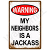 A vintage metal sign with a distressed brown frame and white background featuring the text WARNING MY NEIGHBORS IS A JACKASS 