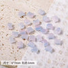 A collection of translucent purple and pink cat head glass beads for jewelry making scattered on a white surface.