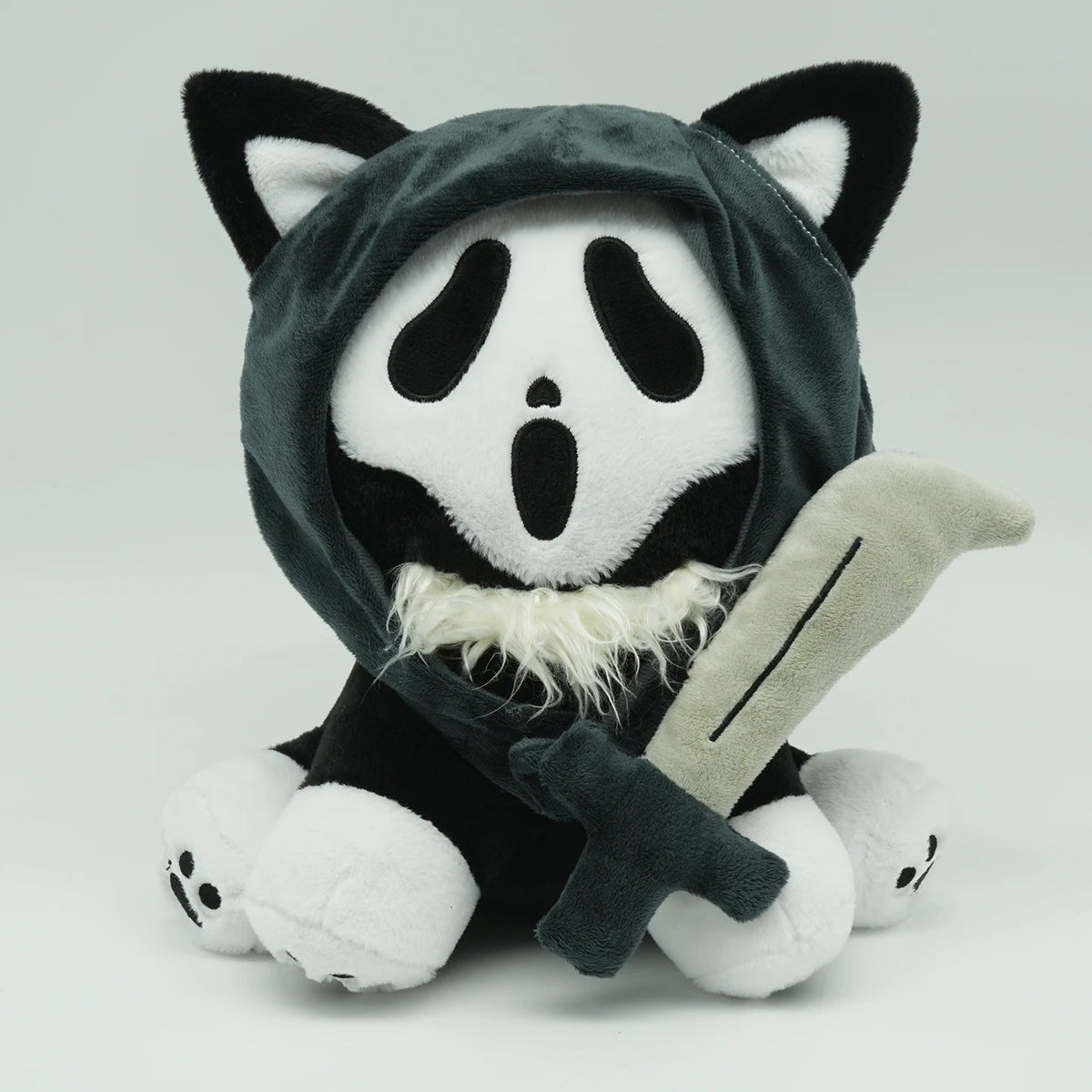 A plush toy resembling a cat face with black and white markings and a hood.
