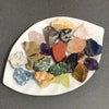 Assorted natural raw crystal stones of various colors and shapes arranged on a white platter.