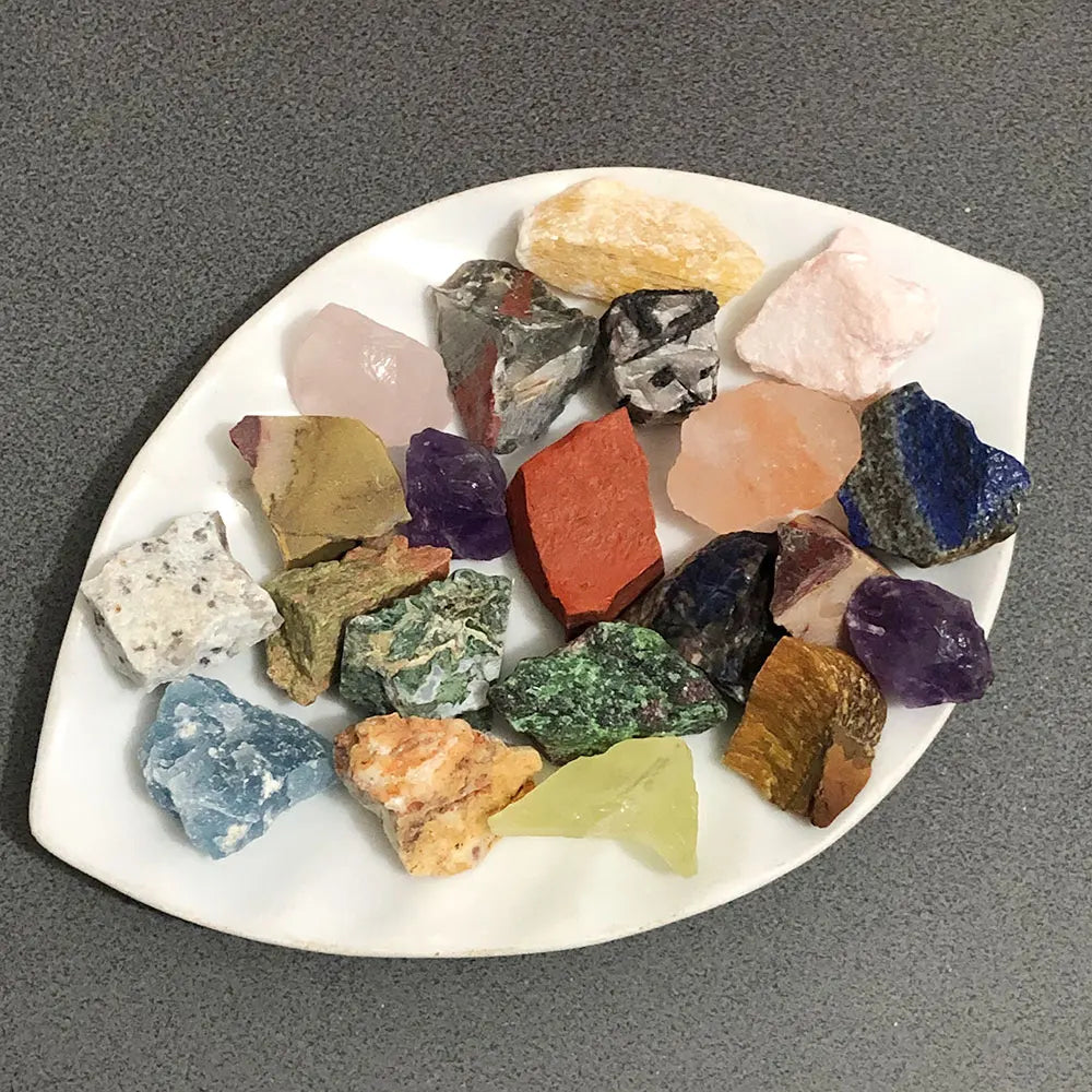 Assorted natural raw crystal stones of various colors and shapes arranged on a white platter.