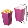 A magenta disposable paper cup with a fluted edge, shown next to a pile of yellow snacks.