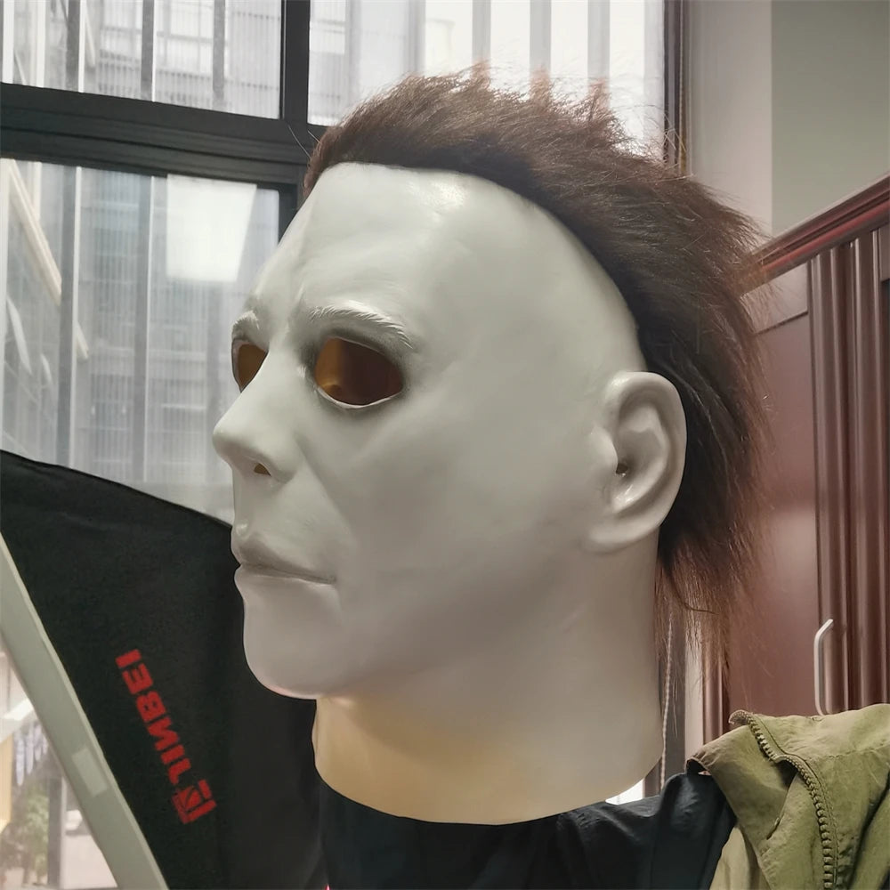 A white latex mask with dark hair is displayed in a studio setting.