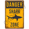 A vintage metal sign with a yellow background and black text warning about a danger shark zone.