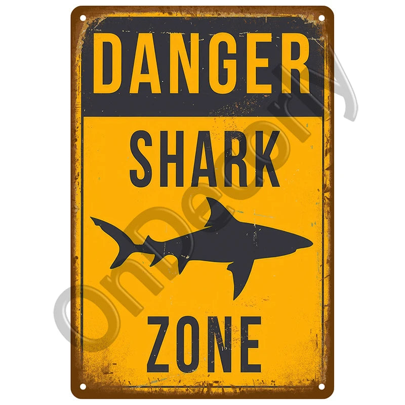 A vintage metal sign with a yellow background and black text warning about a danger shark zone.
