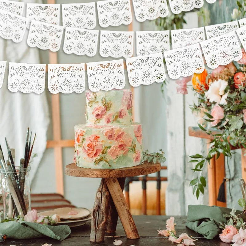 Mehrstöckiger Blumenkuchen mit rosa und grünen Blumen auf Holzständer in heller Umgebung.