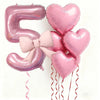 Pink foil balloons shaped like the number 5 and hearts, tied with pink bows and featuring red ribbons for party decor