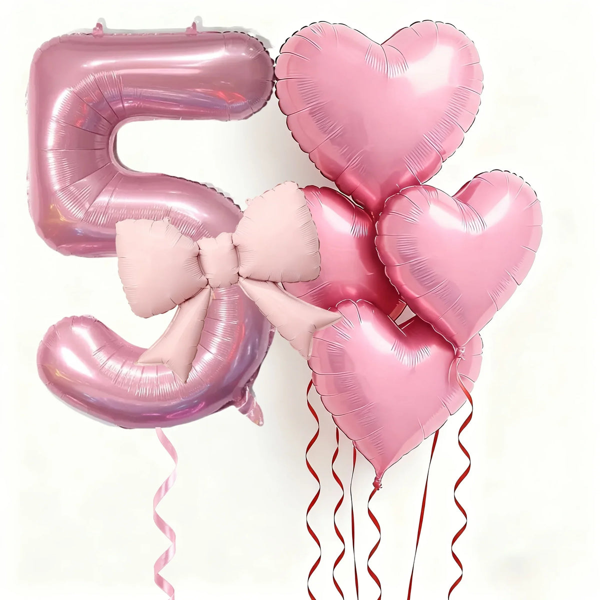 Pink foil balloons shaped like the number 5 and hearts, tied with pink bows and featuring red ribbons for party decor