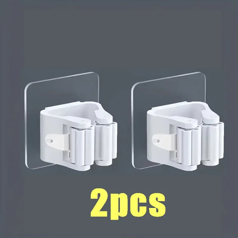 Two white wall mounted holders for storing mops and brooms.
