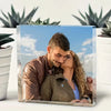 A couple embracing in a photo framed by acrylic glass with a blue sky background.