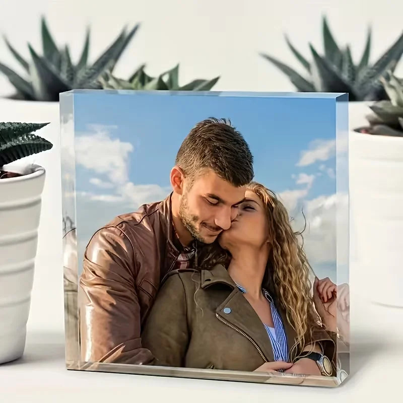 A couple is pictured in a close-up, embracing against a bright blue sky background.